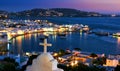 Beautiful view, Mykonos, Greece after sunset from Greek Orthodox church, white cross, bay, ships. Town lights up Royalty Free Stock Photo