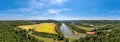 Beautiful view over the curved Isar river in southern bavaria with a wide yellow field and lots of trees at a beautiful