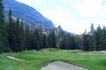 A beautiful view of a par 4 golf hole on a course with a huge mountain in the background, surrounded by forest Royalty Free Stock Photo