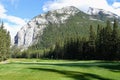 A beautiful view of a par 4 golf hole on a course with a huge mountain in the background, surrounded by forest