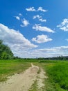 Beautiful view of the path in the park, green grass, blue sky with white clouds on a sunny day Royalty Free Stock Photo