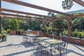 Beautiful view of a patio of a luxurious mansion surrounded by evergreen trees on a sunny day