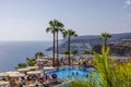 Beautiful view of people bathing in hotel outdoor pool on backdrop of Atlantic Ocean.