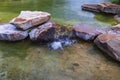 Beautiful view of pond decorated with big rocks. Clear water mirror surface effect Royalty Free Stock Photo