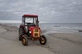 Beautiful view of a red tractor on a sandy beach Royalty Free Stock Photo