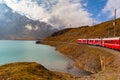 Beautiful view of  Rhaetian railway red train running on the lake side of Lago Bianco, Grisons, Switzerland Royalty Free Stock Photo