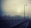 Beautiful view of a road on a foggy bridge with light poles Royalty Free Stock Photo