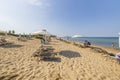 Beautiful view of sandy beach. Parents with children rest under white umbrellas against blue sky. Royalty Free Stock Photo