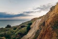 Beautiful view of sandy cliff near sea beach in sunset. Landscape of beach cliff and waves and cloudy sky in sunset or sunrise. Royalty Free Stock Photo
