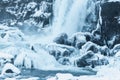 beautiful view of scenic waterfall, frozen river and snow-covered rocks in thingvellir national Royalty Free Stock Photo