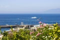 Beautiful view of a sea and boat with pink flowers in the foreground in Capri Island, Naples, Italy Royalty Free Stock Photo