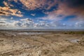 Beautiful view of the sea and breakwaters at low tide in Wierum in the Netherlands. The background is a blue sky with dramatic