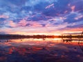 Beautiful view of the smooth lake reflecting the colorful sky at sunset.