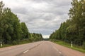 Beautiful view of solitary car on highway with tall green trees on both sides. Road stretches into distance. Royalty Free Stock Photo