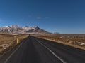 View of straight, empty road with diminishing perspective on Snaefellsnes, western Iceland with rough, snowy mountains. Royalty Free Stock Photo