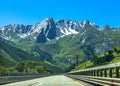 Beautiful view of a straight paved road winding through a forested mountain range in Switzerland Royalty Free Stock Photo