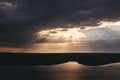 Beautiful view of sun rays from dark clouds above lake. Sunset light over hill and river landscape. Dramatic moody scenery. Bakota Royalty Free Stock Photo