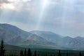 Beautiful view of the sunbeams penetrating through the clouds above green mountains.