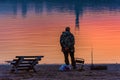 Fisherman on the river bank at sunset