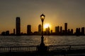 A beautiful view during sunset on the Hudson River and the sun setting between the sky-line of Jersey City, New York, USA Royalty Free Stock Photo