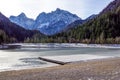 Beautiful view at sunset of the peaceful lake Fucine Tarvisio, Italy with green forest and snowy mountains in the Royalty Free Stock Photo