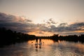 Beautiful view of sunset and river on which pair of people swim on the sup boards