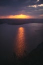 Beautiful view of sunset warm light from dark clouds above lake. Sunny rays over hill and river landscape. Dramatic moody scenery Royalty Free Stock Photo