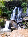 a beautiful view of the swift waterfall that pours through the pile of rocks towards downstream with shades of green trees.