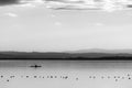 Beautiful view of Trasimeno lake at sunset with birds on water, a man on a canoe and hills on the background Royalty Free Stock Photo