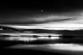 Beautiful view of Trasimeno lake Umbria, Italy at dusk, with black and white tones and moon in the sky Royalty Free Stock Photo
