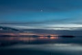 Beautiful view of Trasimeno lake Umbria, Italy at dusk, with blue and orange tones and moon in the sky Royalty Free Stock Photo