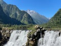 Beautiful view of a waterfall and mountains under a clear blue sky. Royalty Free Stock Photo