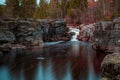 Beautiful view of a waterfall surrounded by rocks and evergreen trees. Royalty Free Stock Photo