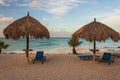 Beautiful view of white sand Aruba beach. Blue sunbeds under sun umbrellas on turquoise water and blue sky with white clouds. Royalty Free Stock Photo