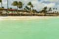 Beautiful view of white sand Aruba beach. Blue sunbeds under sun umbrellas on turquoise water and blue sky. Royalty Free Stock Photo