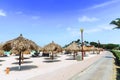 Beautiful view of white sand beach with sun umbrellas and sun beds on green palm trees and blue sky with white clouds background Royalty Free Stock Photo