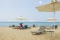 Beautiful view of white sand Greece beach. Sunbeds under sun umbrellas on turquoise water and blue sky. Royalty Free Stock Photo