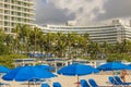 Beautiful view of white sandy beach Atlantic ocean with sun loungers and parasols against backdrop of palm trees and buildings. Royalty Free Stock Photo