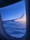 Beautiful view through the open window in airplane on the wing and clouds at sunrise litght Royalty Free Stock Photo