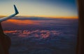 Beautiful view from the window porthole. the wing of an airplane on sunset sky background with clouds highlighted in