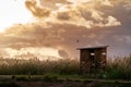 Beautiful view of a wooden watch tower on green field under dramatic sunset sky Royalty Free Stock Photo