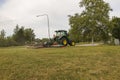 Beautiful view of worker on modern lawn mower machine taking care of town grass field