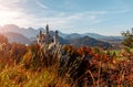 Beautiful view of world-famous Neuschwanstein Castle with Alpine mountains on Background, under sunlit. Wonderful sunny landscape