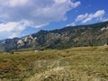 Wyoming landscape, with thick white cottony clouds in the skies and cabins at the foot of the mountains