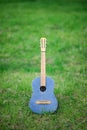 Beautiful vintage jeans acoustic classical guitar with nylon strings with wooden neck standing on vivid green grass Royalty Free Stock Photo