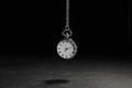 Beautiful vintage pocket watch with silver chain on black background above dark table. Hypnosis session Royalty Free Stock Photo