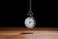 Beautiful vintage pocket watch with silver chain on black background above wooden table. Hypnosis session Royalty Free Stock Photo