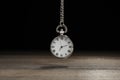 Beautiful vintage pocket watch with silver chain on black background above wooden table. Hypnosis session Royalty Free Stock Photo