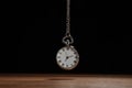 Beautiful vintage pocket watch with silver chain on black background above table. Hypnosis session Royalty Free Stock Photo