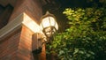 A beautiful vintage street lamp located on the wall of an old red brick house. The lantern illuminates the street at Royalty Free Stock Photo